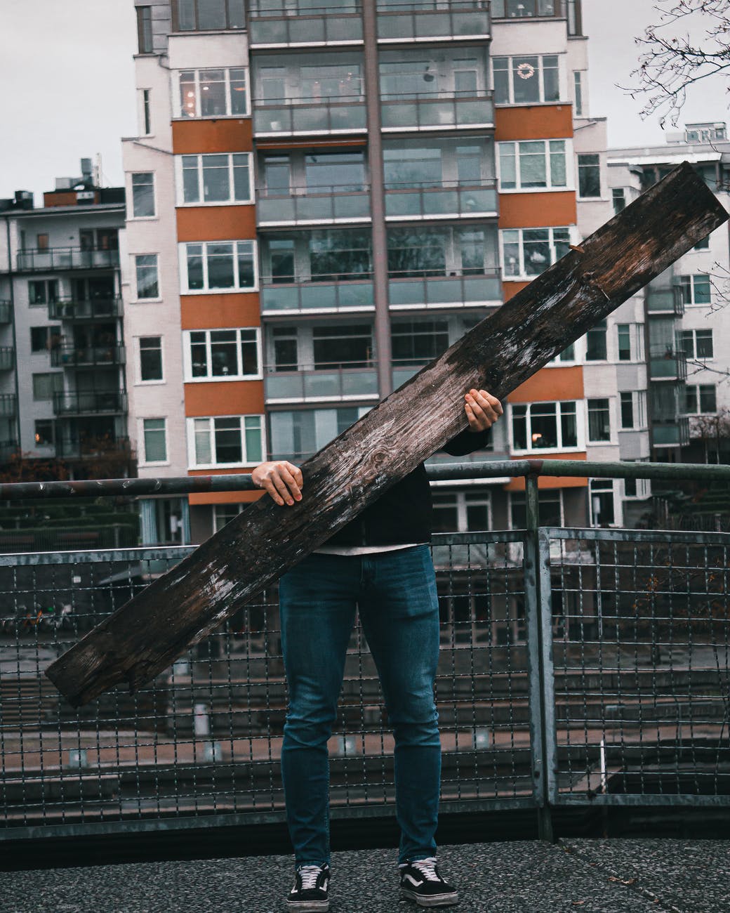 person in blue denim jeans standing holding brown wooden log