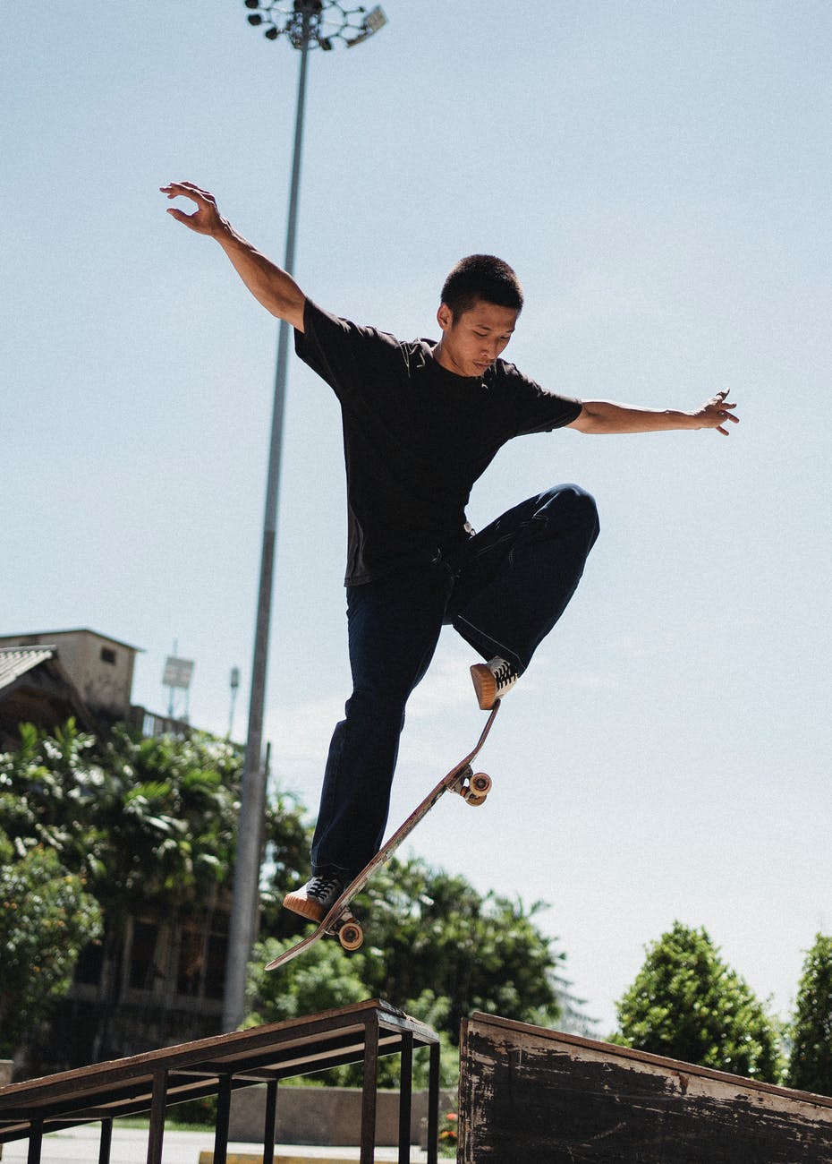 sportive asian man doing trick on skateboard