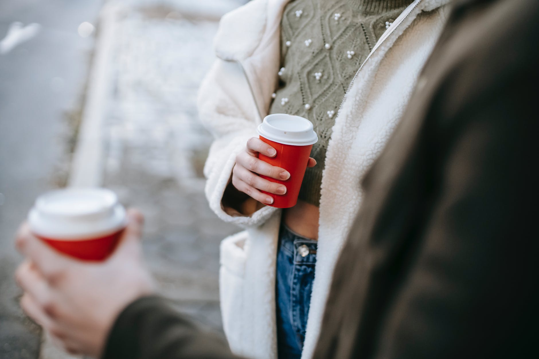 crop couple drinking takeaway beverages on street