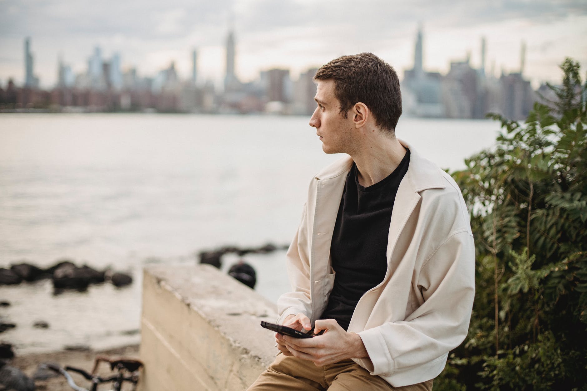 thoughtful man texting on smartphone on embankment