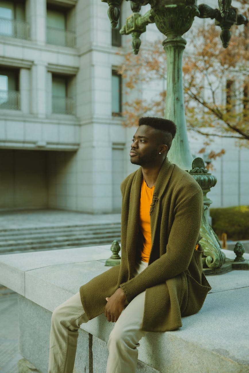 stylish black man sitting on stone border