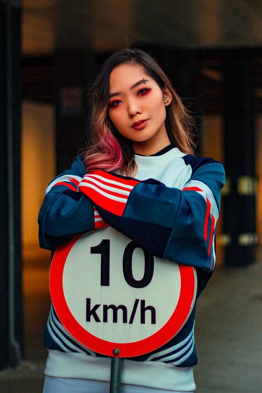 photo of woman leaning on road sign