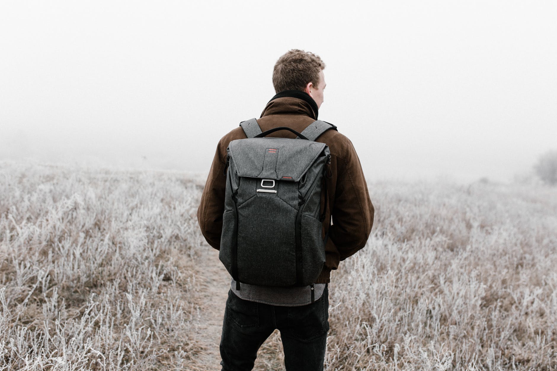 man standing on field carrying a back pack