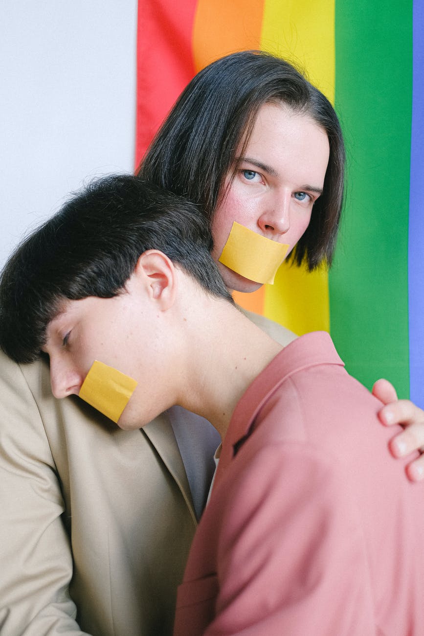 two men with adhesive tape over their mouth hugging