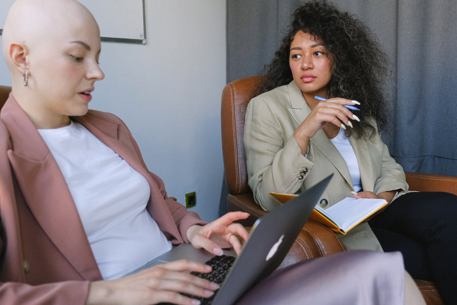 serious female colleagues having conversation sitting in armchairs