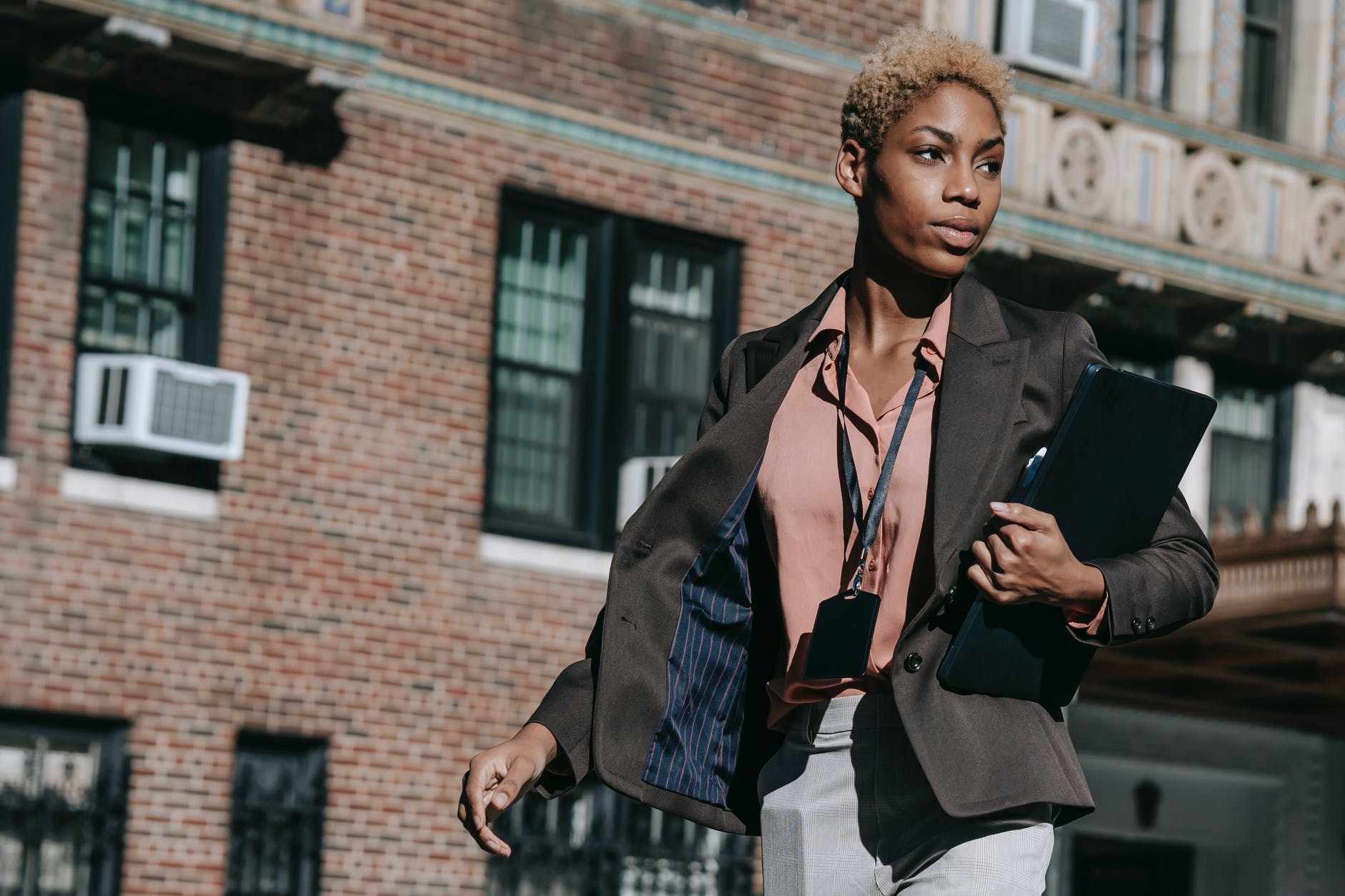 stylish young ethnic lady strolling on street during break on sunny day