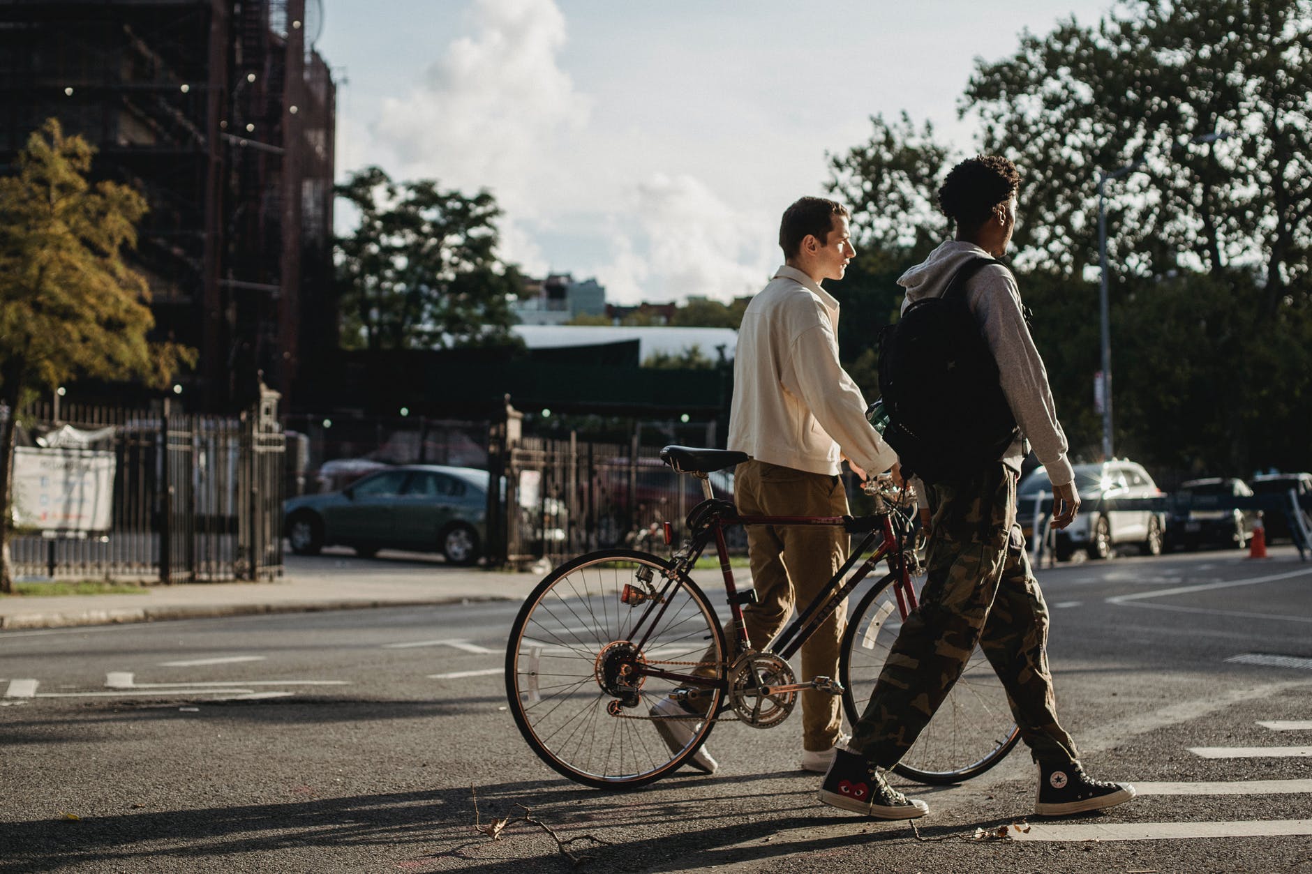 young diverse male friends strolling on crosswalk in city residential district