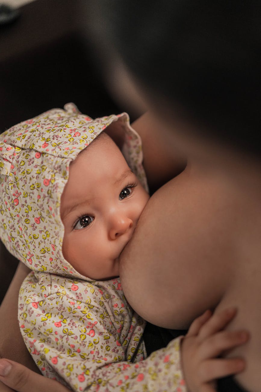 unrecognizable woman suckling cute newborn child