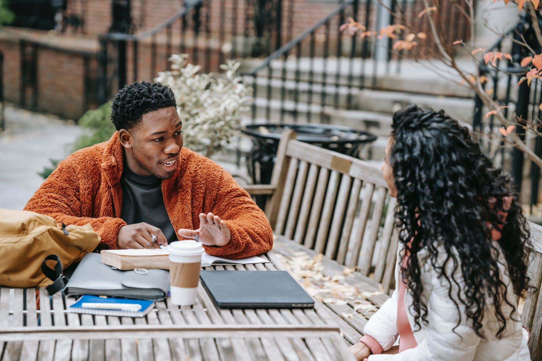 diverse young students discussing education at table with laptop