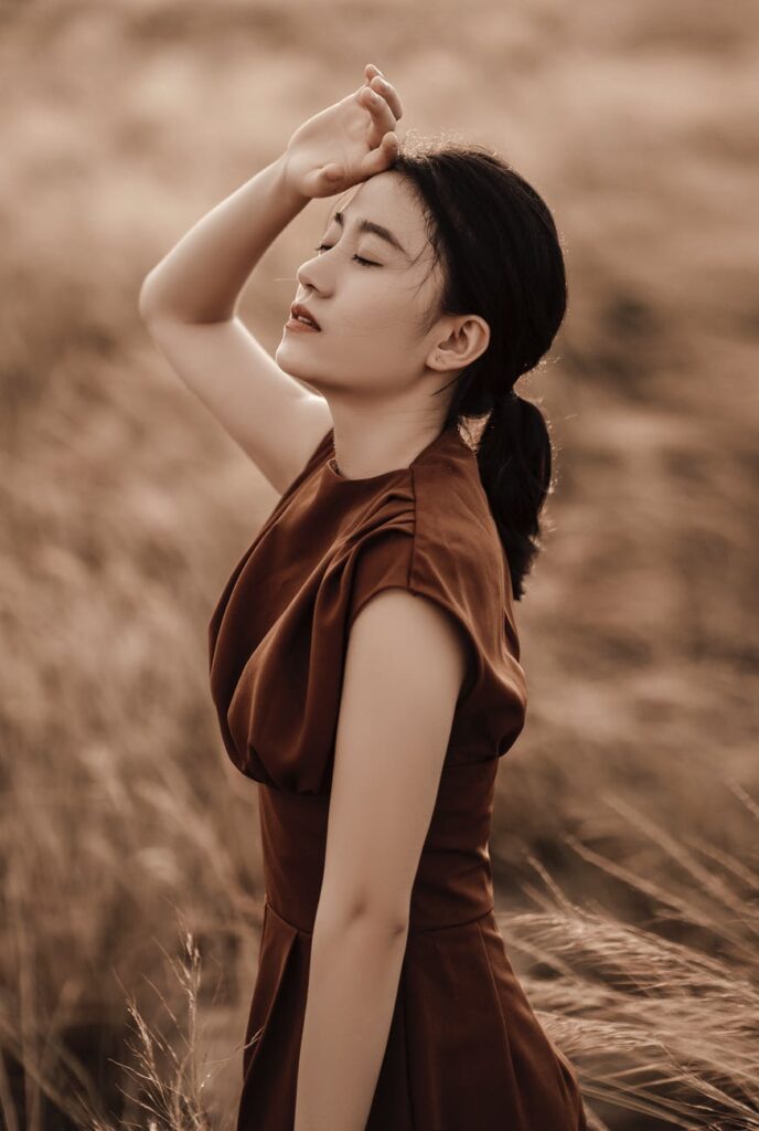 sensitive ethnic woman touching forehead in countryside field