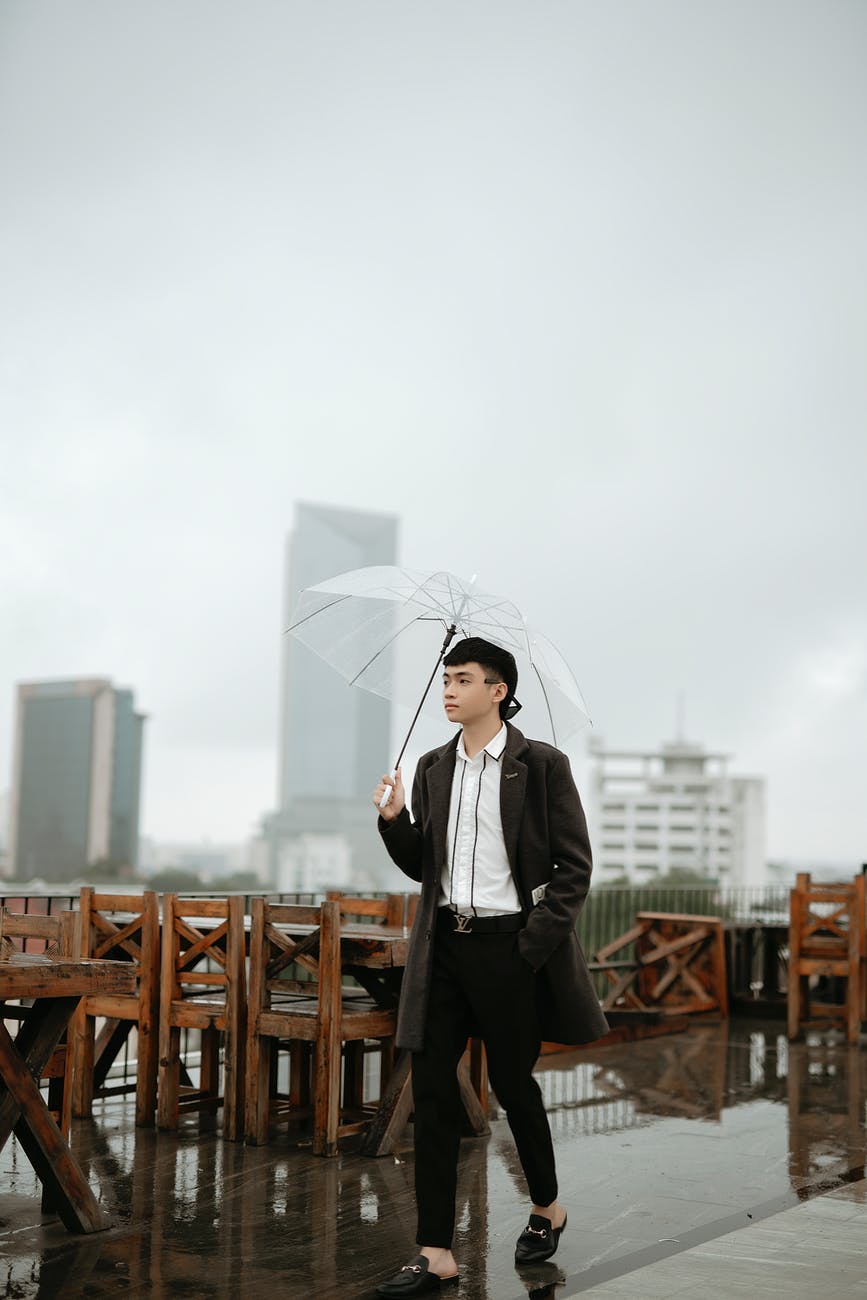 stylish asian man walking on cafe terrace in city