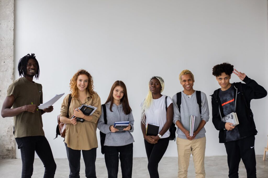 positive multiethnic team of students standing with books