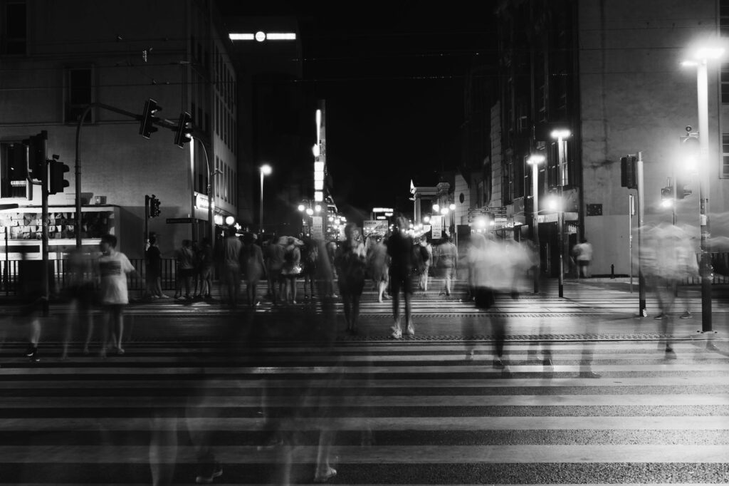 group of people crossing pedestrian lane in greyscale