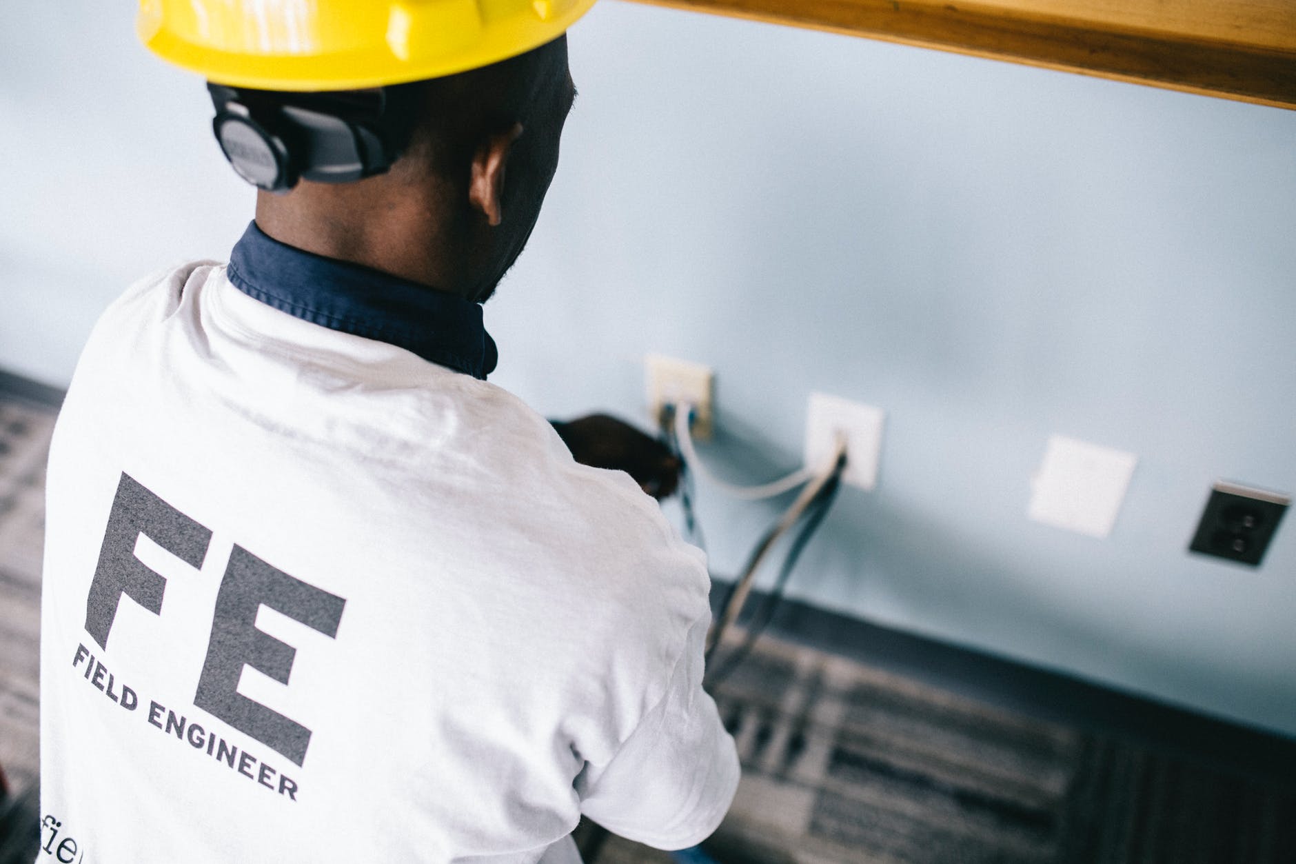 professional ethnic engineer in hardhat examining wall plugs