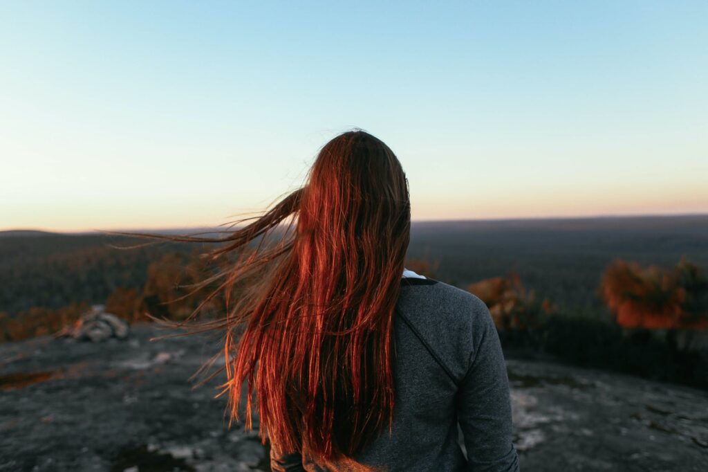 anonymous woman on mountain enjoying view of valley with woods