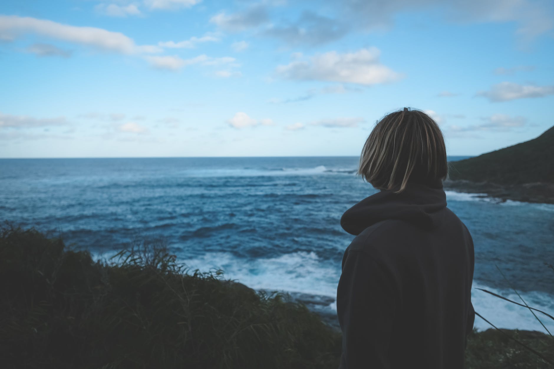 anonymous woman admiring wavy blue sea during trip at sundown