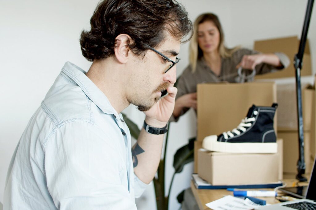 man on the phone while woman busy packing