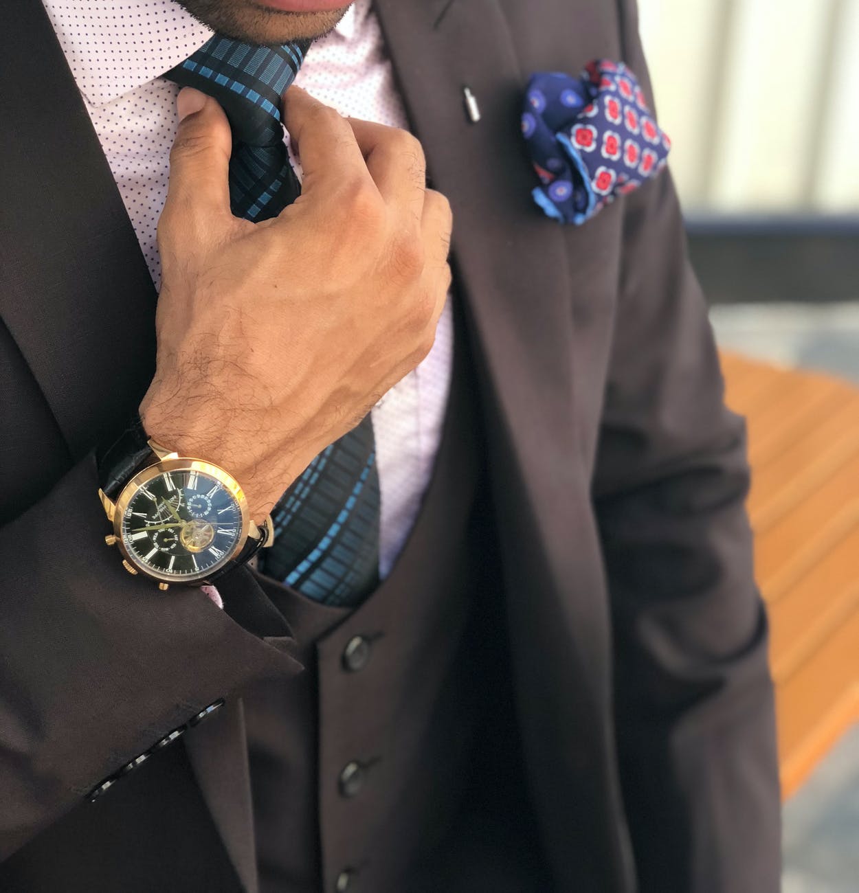 man in formal suit jacket holding his necktie