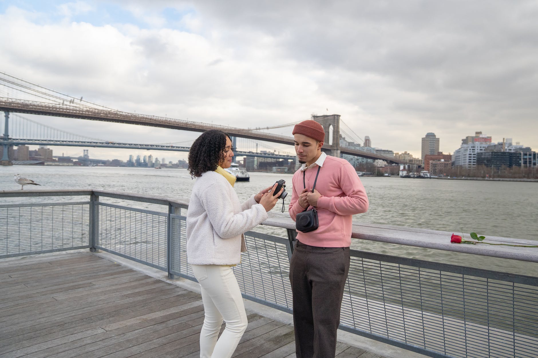 hispanic couple looking at photos on analog camera near river