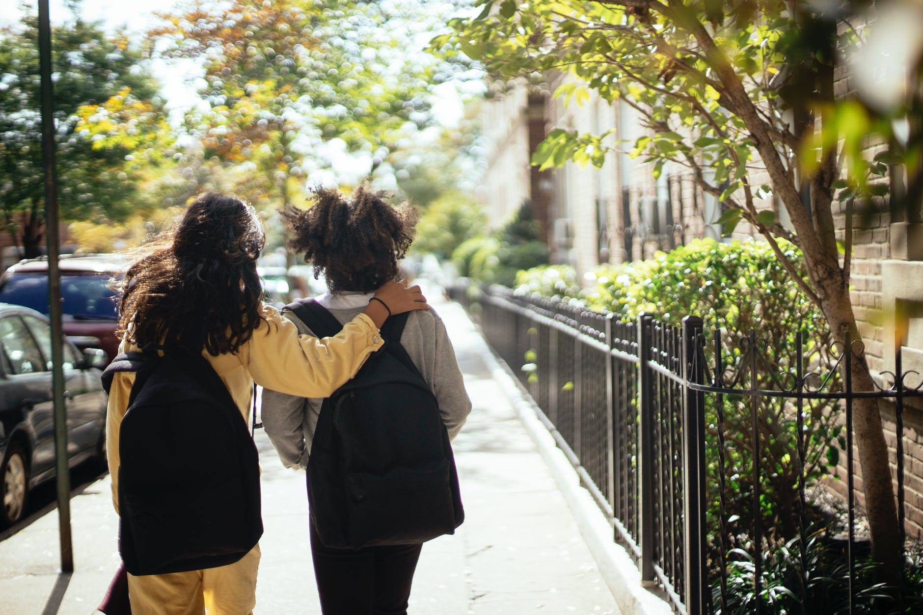 anonymous schoolgirls with backpacks walking together