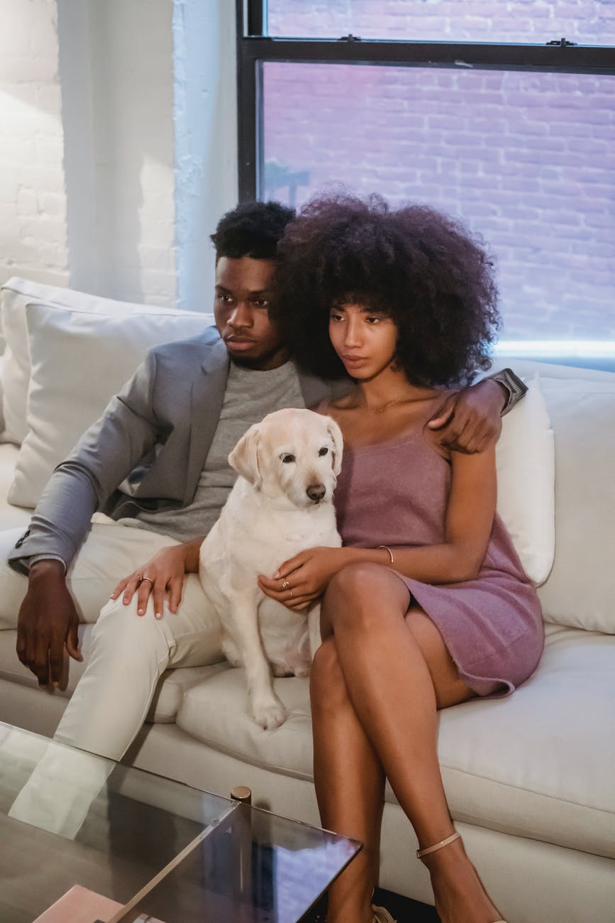 black couple sitting on sofa with dog