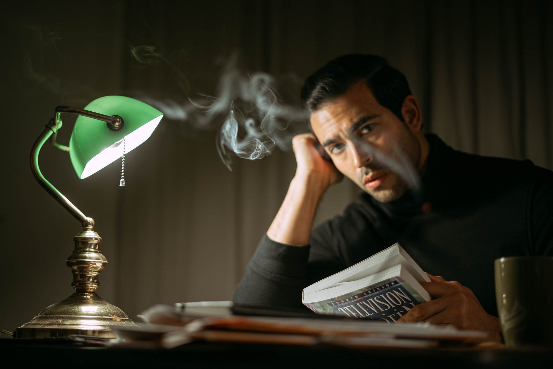 elegant man with book at table with retro lamp