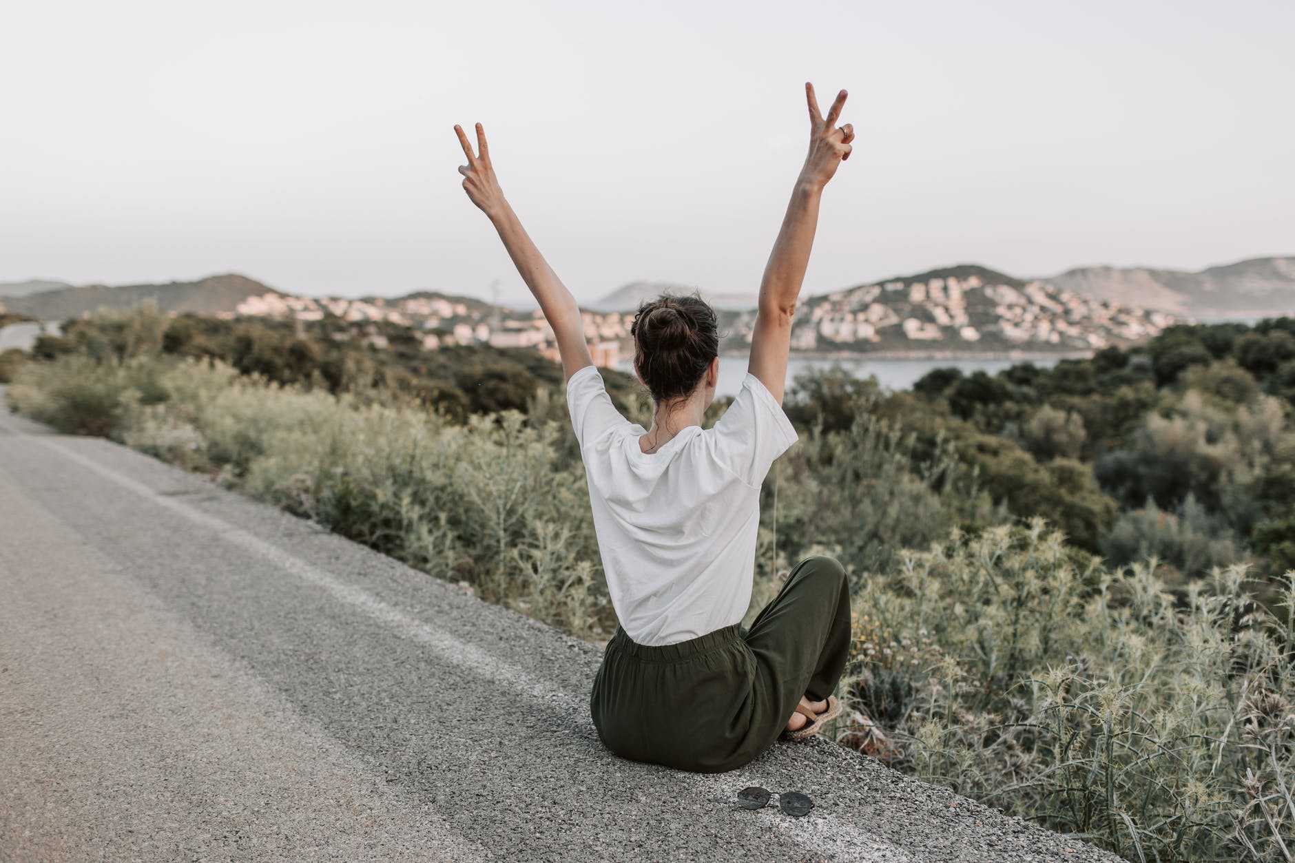 woman sitting on the road making a peace sign