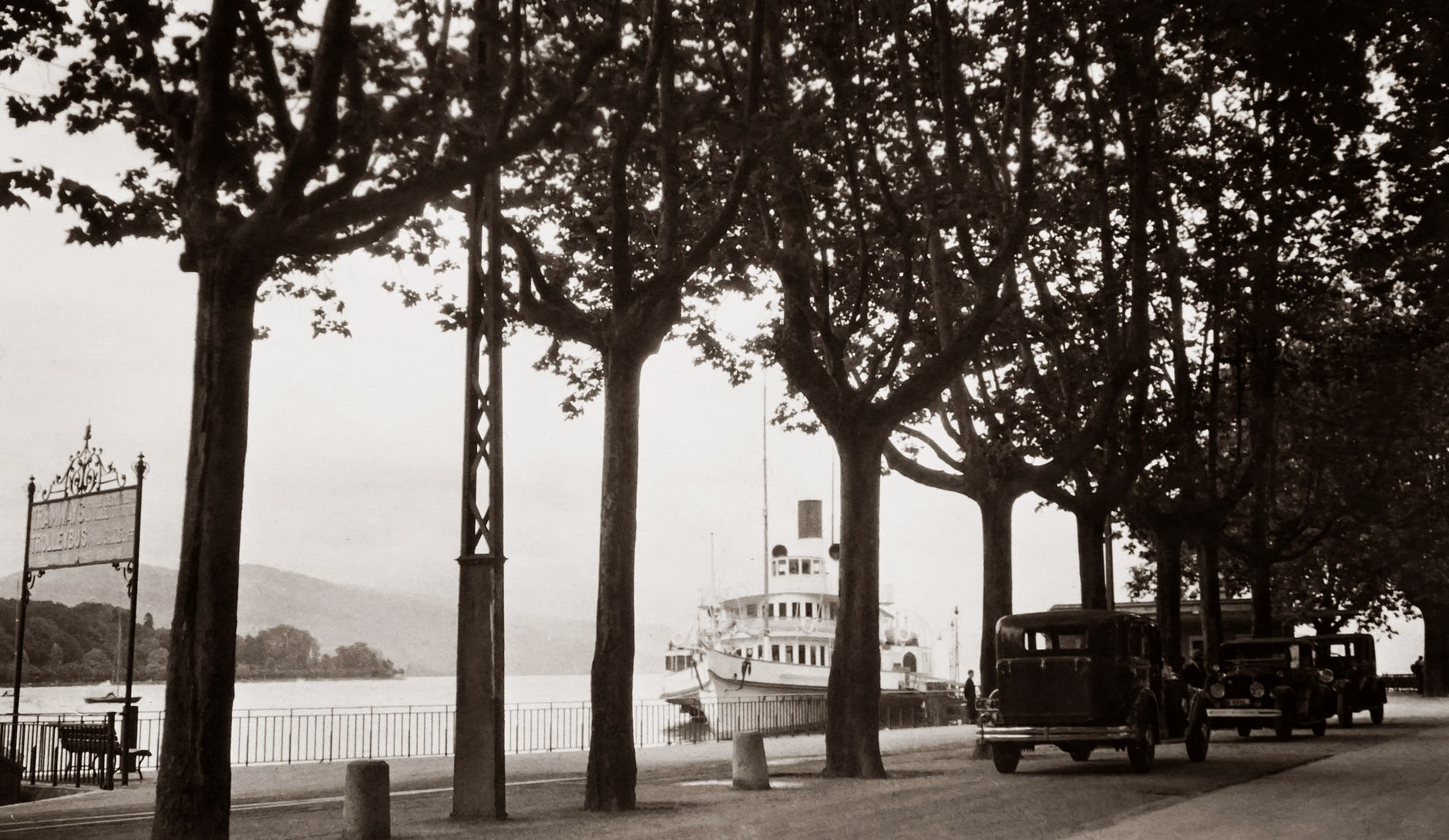 an old photo of cars parked on the street near a docking area