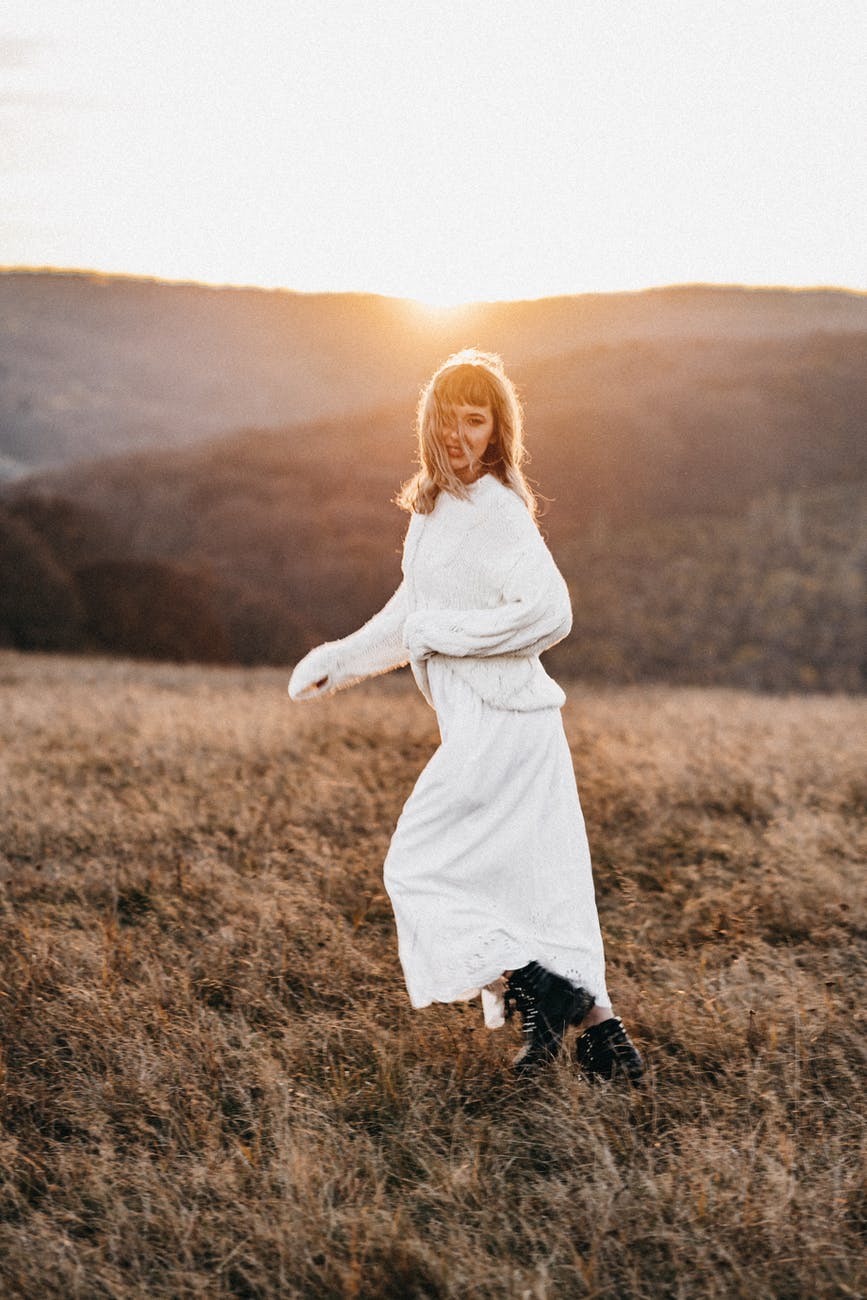 smiling woman running in countryside field in sunshine