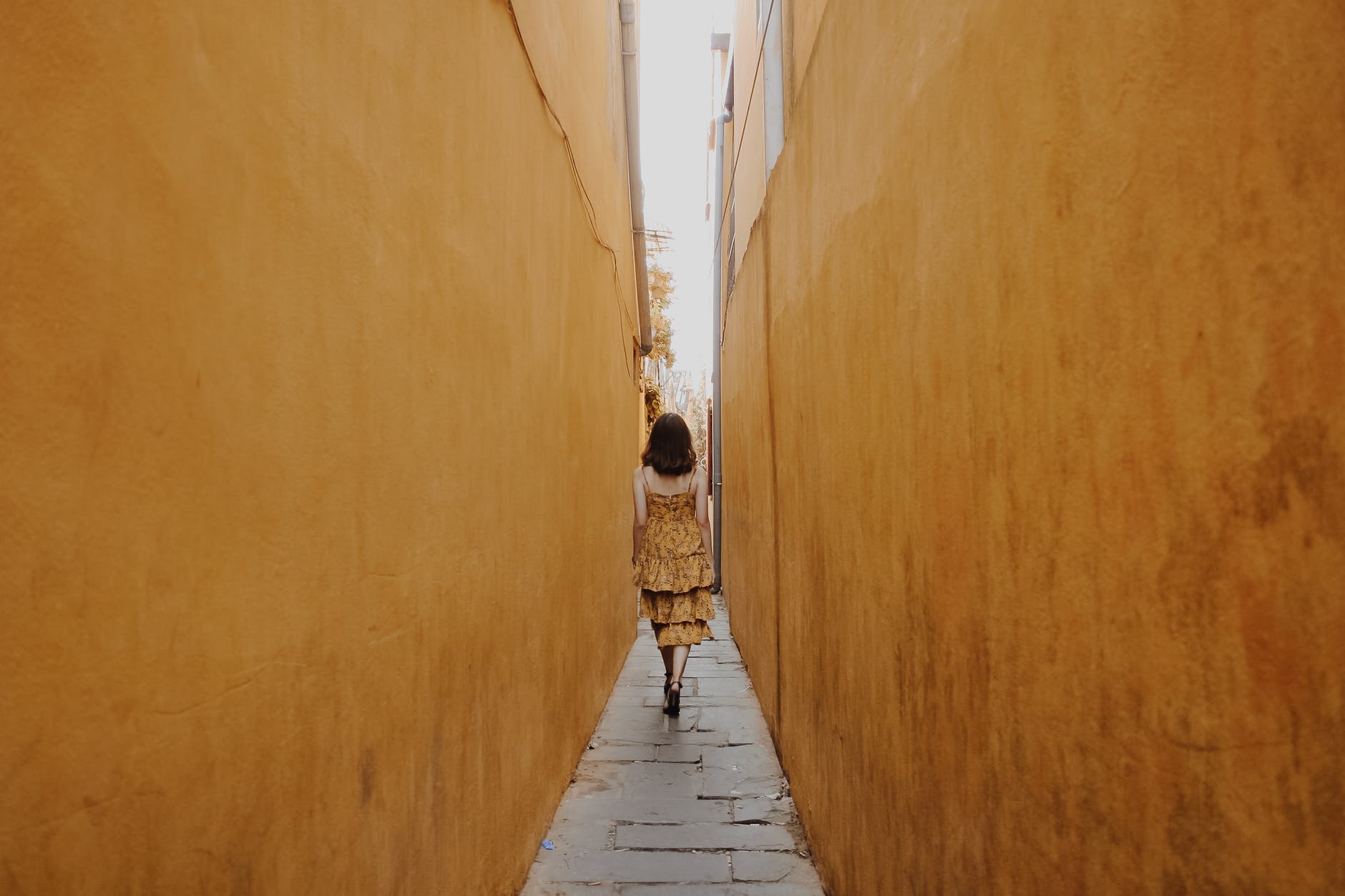 back view of a woman walking in a narrow alley