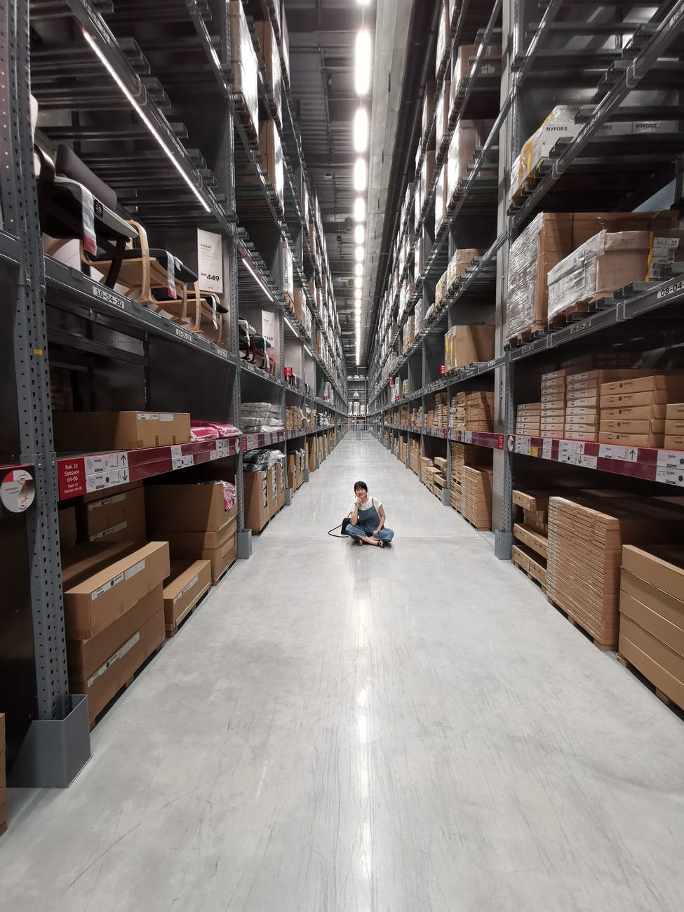 person sitting on ground between brown cardboard boxes