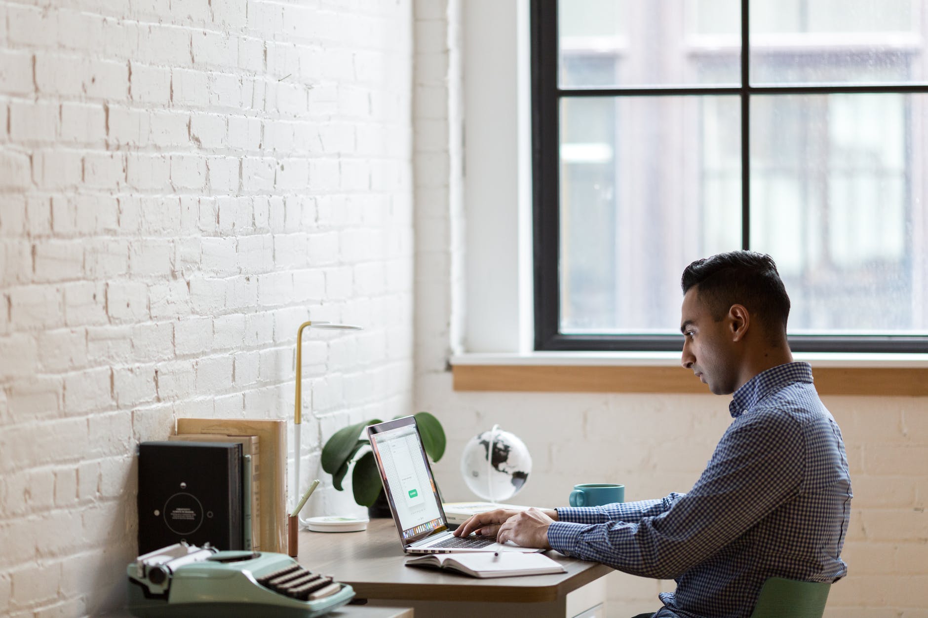 man sitting on green chair while using laptop