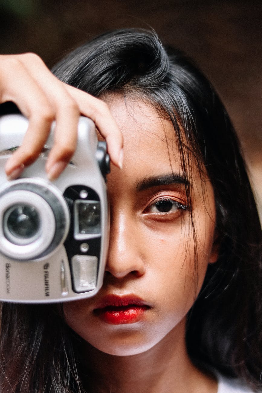 photo of woman holding silver camera