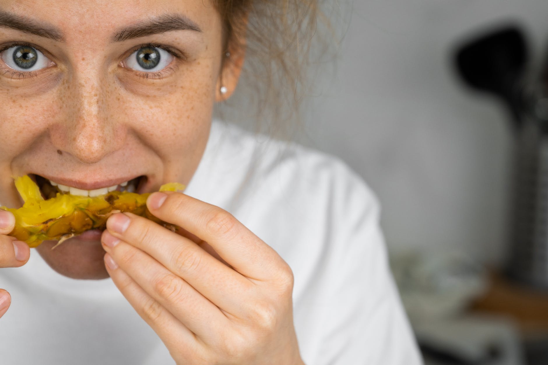 happy woman eating pineapple at home