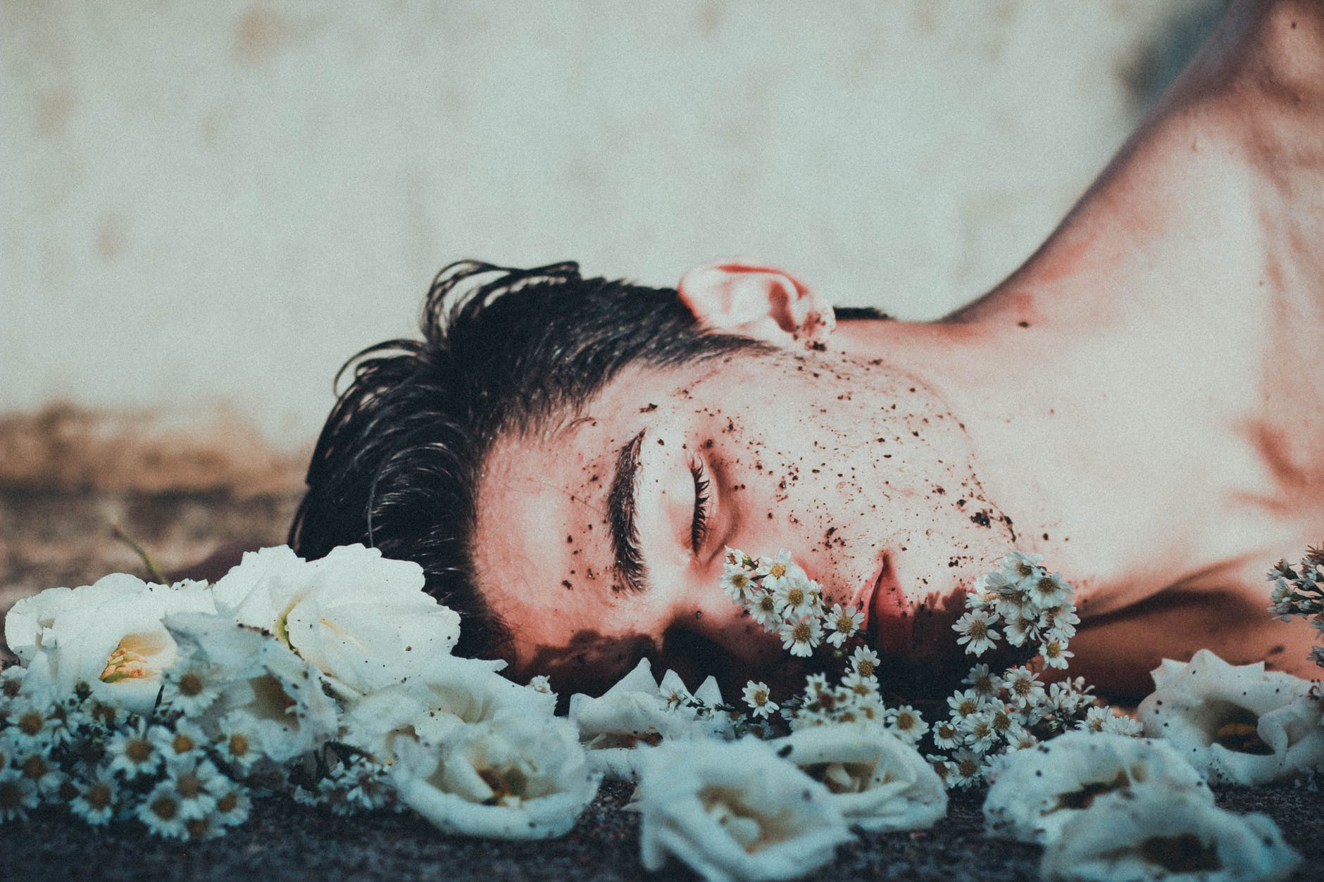 man lying on white flowers