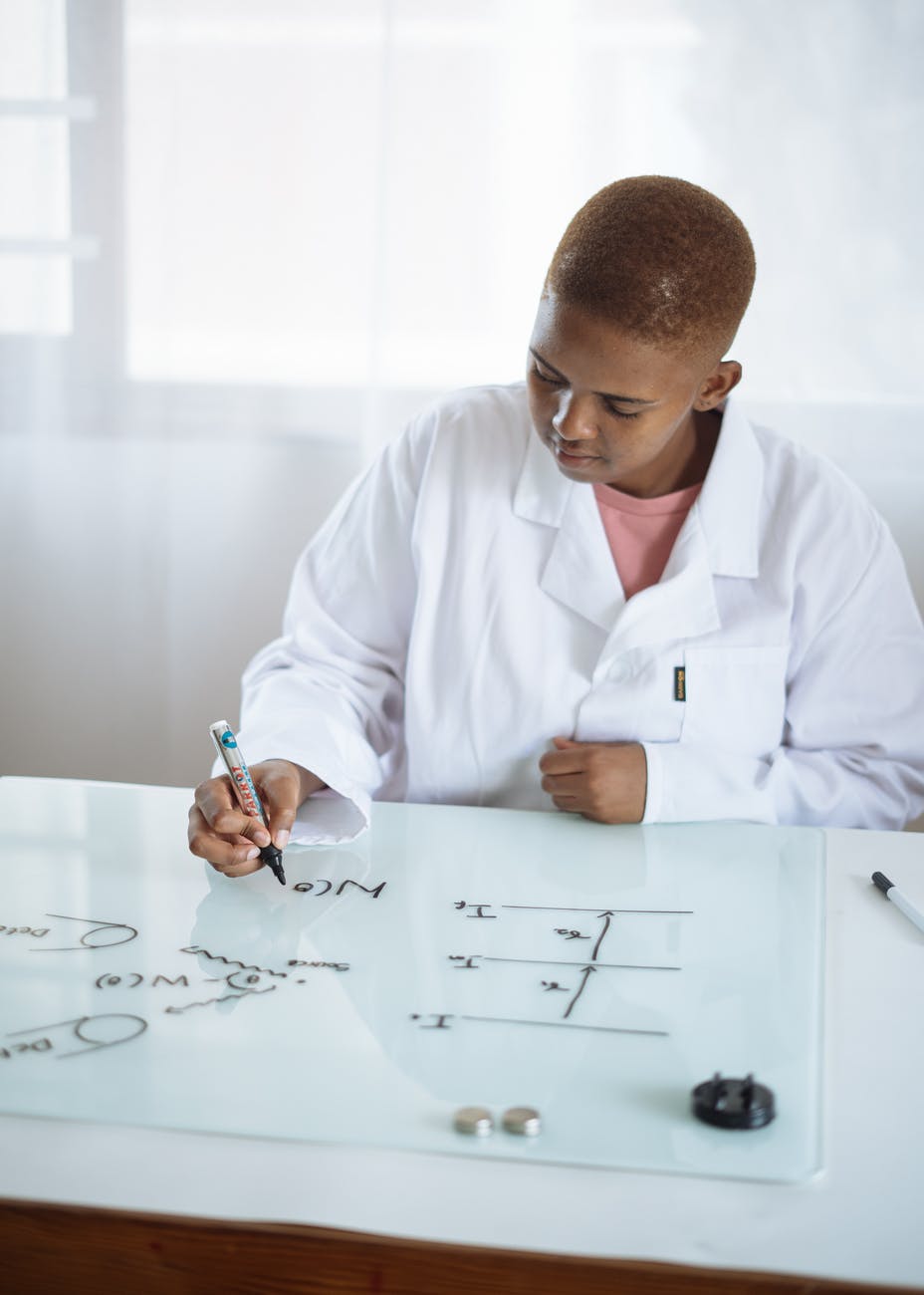 clever african american student displaying chemical formula on magnetic whiteboard