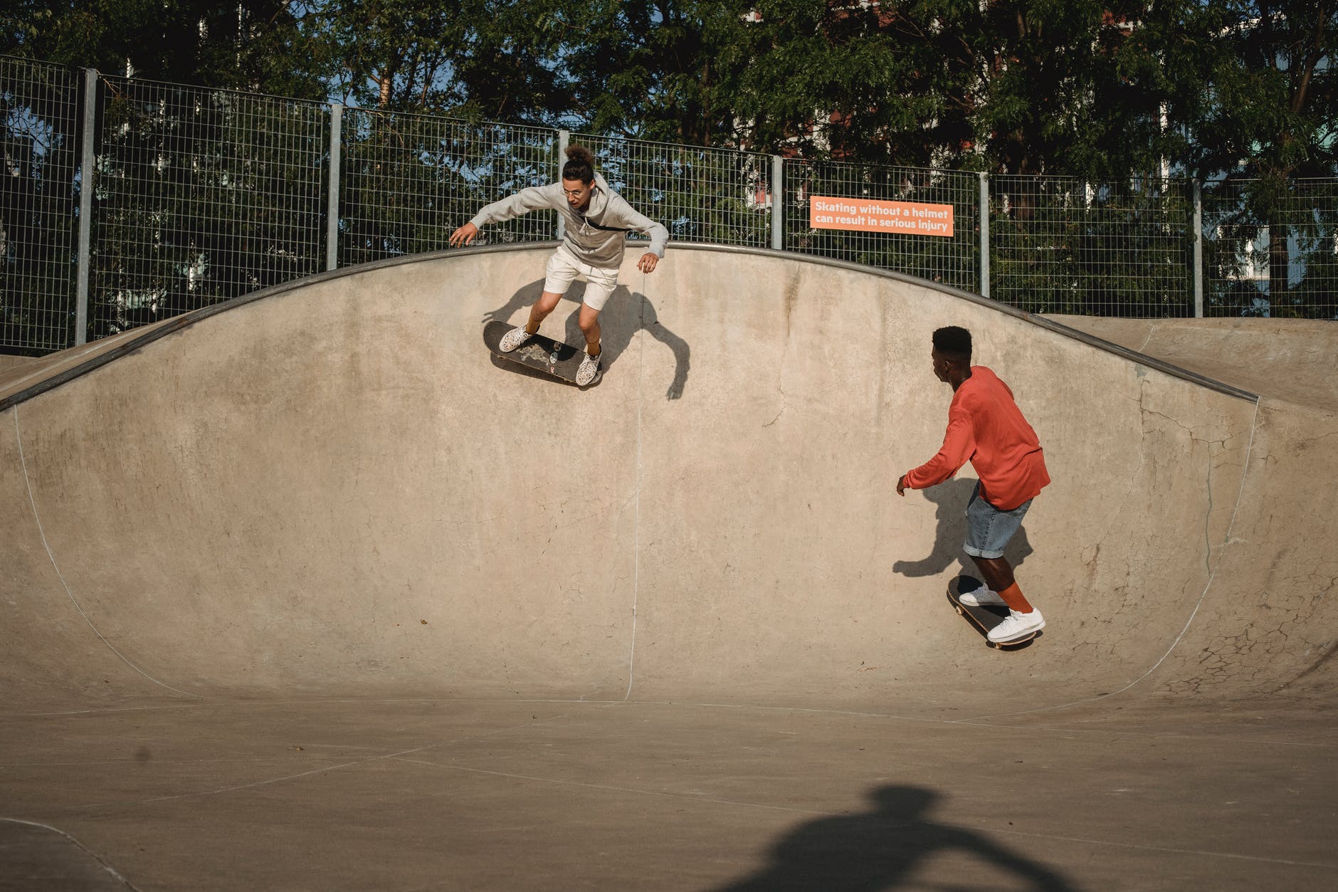 active young skateboarders riding skateboards on slope of ramp on sunny day